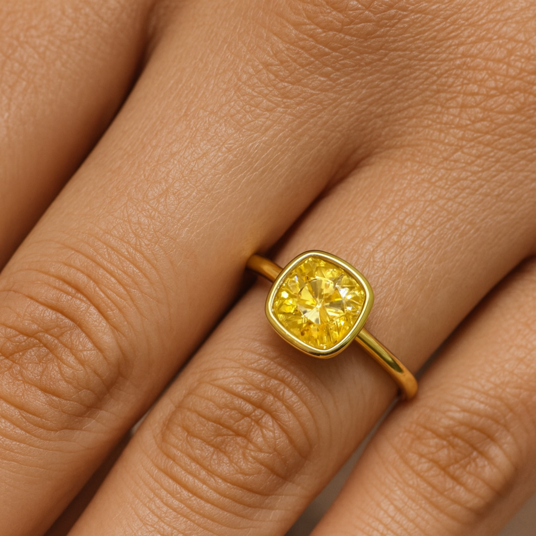 Cushion Cut Yellow Moissanite Engagement Ring Shown on the Finger, Simple Bezel Set Solitaire Yellow Diamond Alternative in Minimalist Design | Rare Earth Jewelry