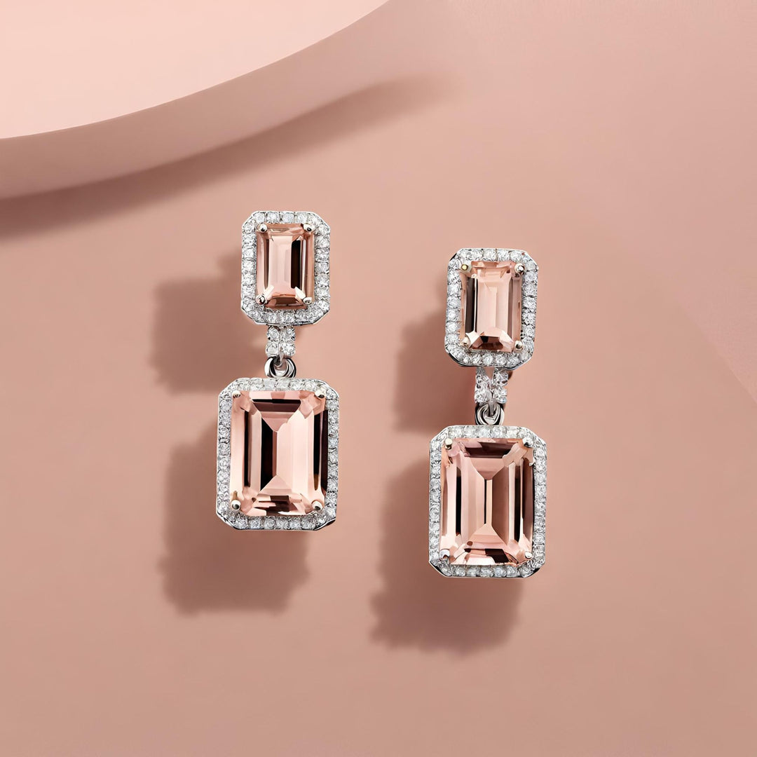 A pair of emerald cut natural Morganite earrings in two-stone diamond halo design. 14K White Gold settings, natural peachy pink gemstone earrings for a bride.