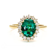 Oval green emerald and diamond ring in a vintage style halo design.  Green stone engagement ring with diamonds.