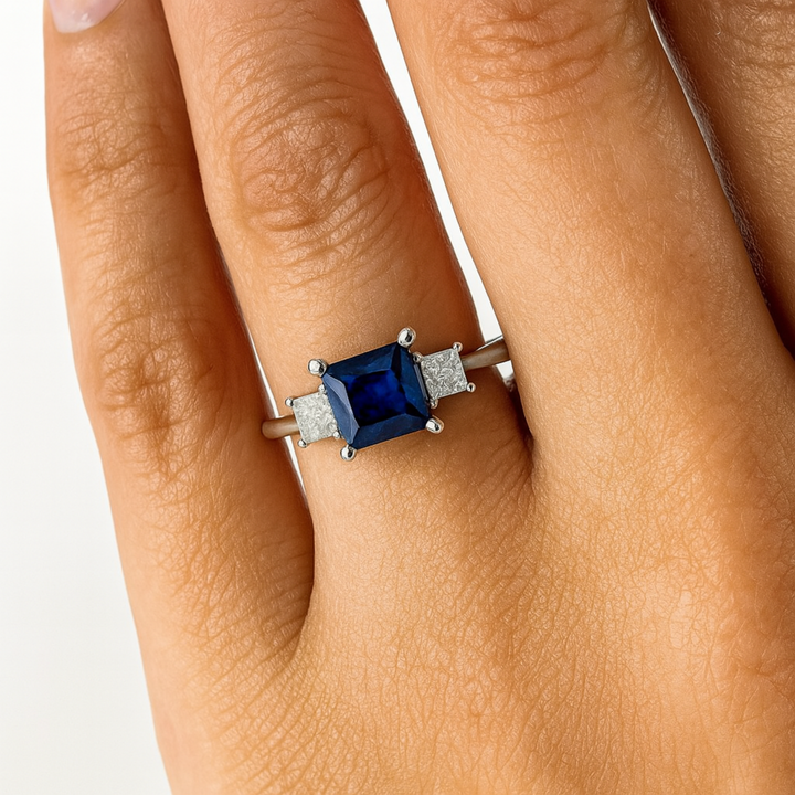 Princess Cut Blue Sapphire Engagement Ring with a 3 Stone Design and Diamond Accents, Ring shown on Hand | Rare Earth Jewelry
