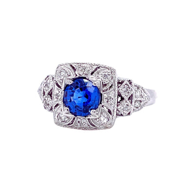 An Art Deco style natural Blue Sapphire ring with pave set diamonds.  This antique style ring has a round Ceylon sapphire and a square shaped design with openwork and milgrain beaded edge details..