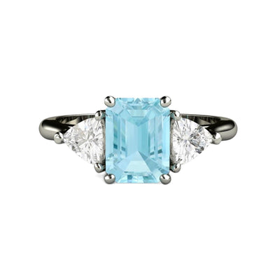 A three stone style Aquamarine engagement ring with an 8x6mm emerald cut natural Aquamarine and two natural White Sapphire trillion side stones.