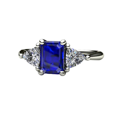 An emerald cut Blue Sapphire engagement ring in a three stone style with diamond trillions in gold or platinum from Rare Earth Jewelry.