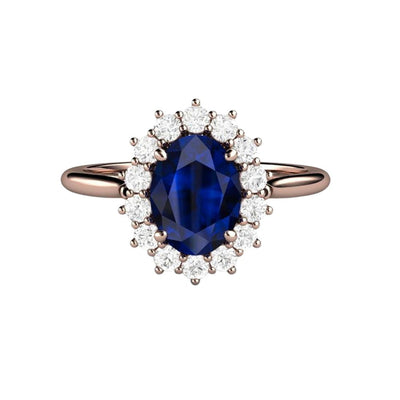An oval Blue Sapphire engagement ring in a vintage inspired Princess Diana style diamond halo cluster design, shown here in rose gold from Rare Earth Jewelry.