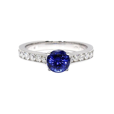A blue sapphire solitaire engagement ring with a round sapphire center stone and diamond accents in the band from Rare Earth Jewelry.