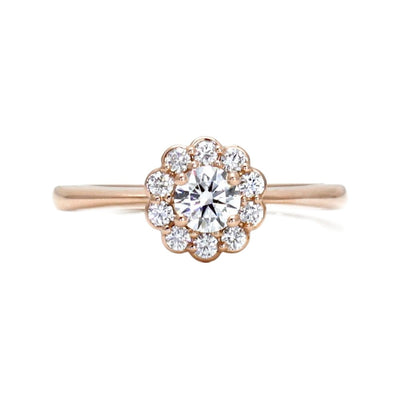 A romantic and feminine styled diamond engagement ring with a flower shaped diamond halo or cluster surrounding a .30ct natural diamond center, shown in rose gold from Rare Earth Jewelry