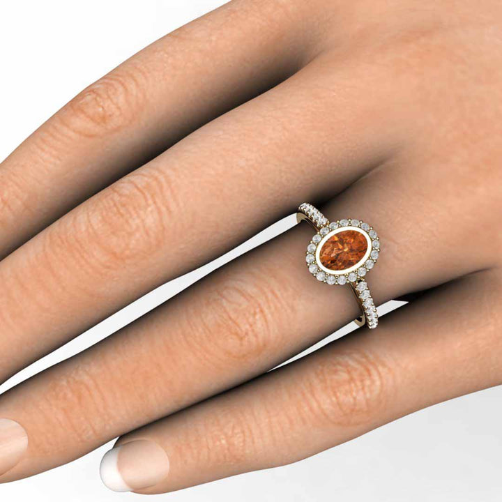 Oval Orange Sapphire Engagement Ring on the Finger, Bezel Seting with Pave Set Diamonds | Rare Earth Jewelry