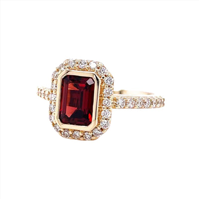 Emerald cut red Mozambique Garnet engagement ring with bezel set design with pave diamond halo shown in yellow gold from Rare Earth Jewelry.