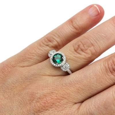 A round emerald and diamond engagement ring in a 3 stone halo style in gold or platinum from Rare Earth Jewelry