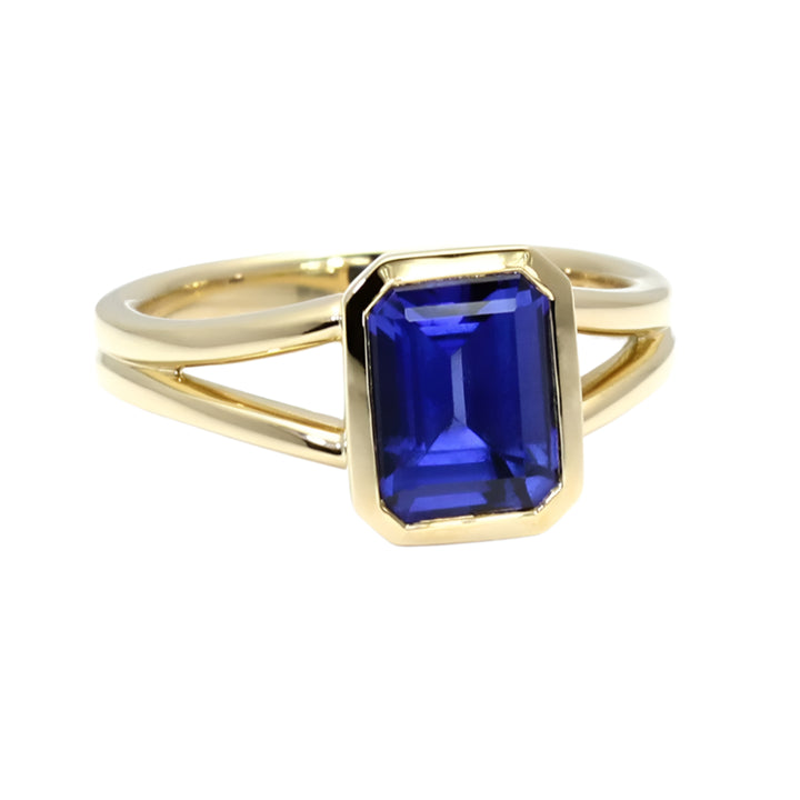 Emerald cut blue sapphire engagement ring in bezel setting with split shank in yellow gold | Rare Earth Jewelry