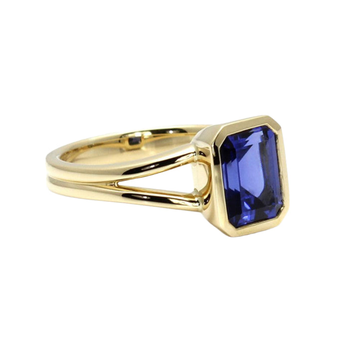 Side view of yellow gold Sapphire ring with split shank and bezel set emerald cut Sapphire.  September Birthstone Ring | Rare Earth Jewelry
