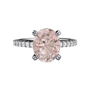 A Morganite engagement ring in an oval solitaire design with double prongs and pave set diamonds on the band. Natural peach pink stone engagement ring from Rare Earth Jewelry.