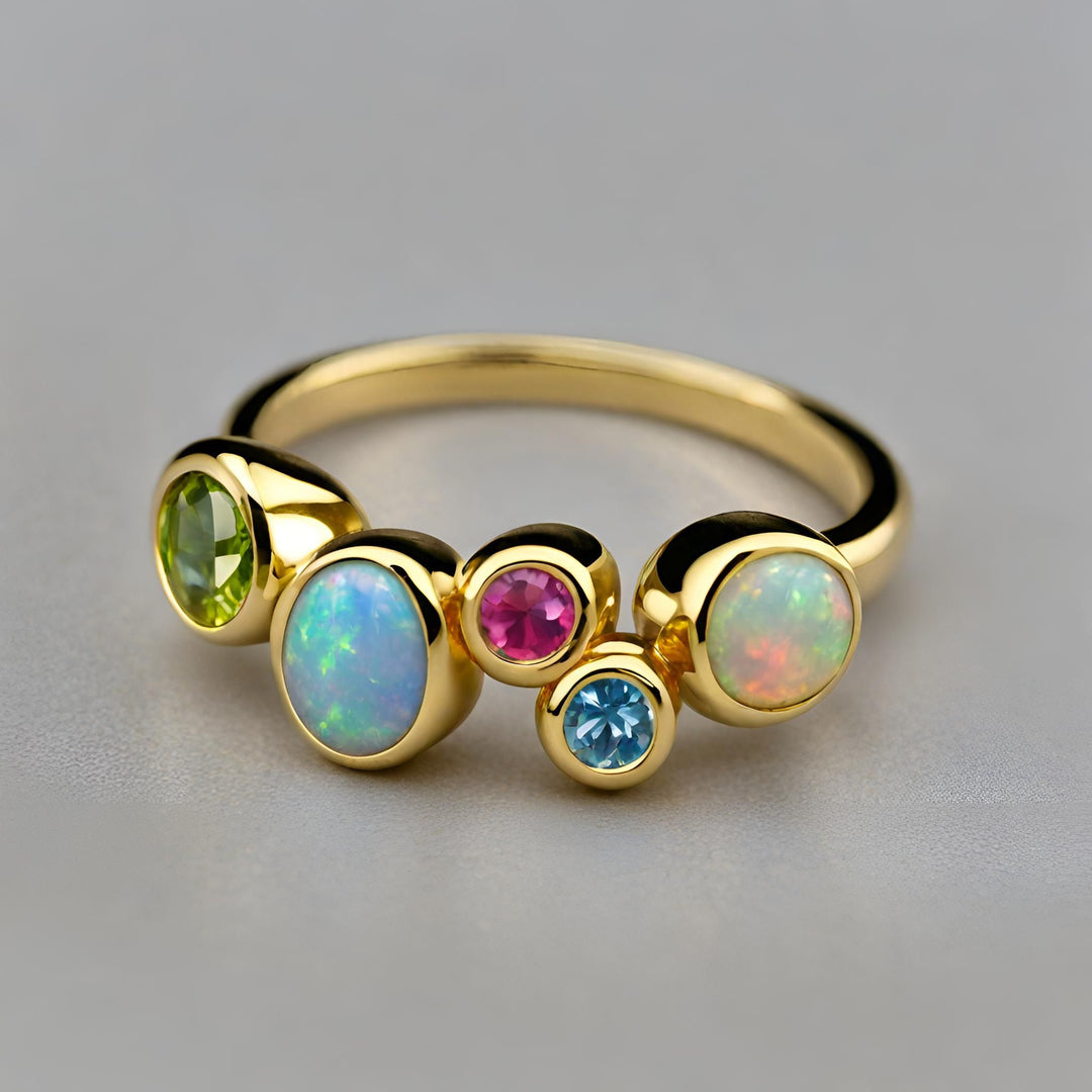 A 14K Gold Modern Multistone Ring with colorful Birthstones including Opal, Peridot, Tourmaline and Aquamarine in a freeform bezel set design from Rare Earth Jewelry.