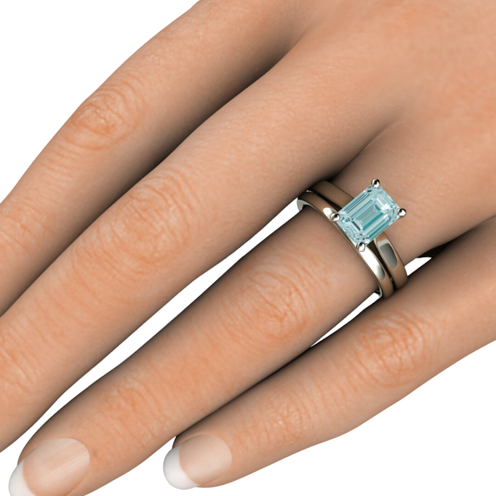 Emerald cut Aquamarine solitaire engagement ring and wedding band hand shot from Rare Earth Jewelry.