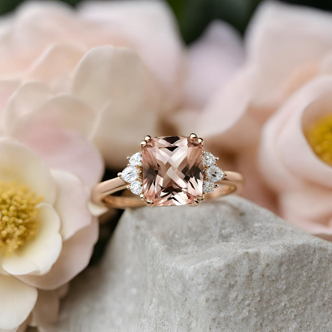 A cushion cut natural Morganite engagement ring with three diamonds on each side in a rose gold setting with double prongs from Rare Earth Jewelry.