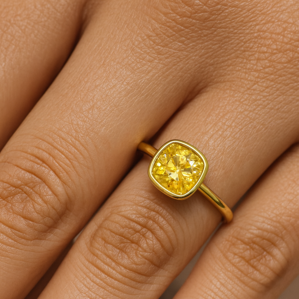Cushion Cut Yellow Moissanite Engagement Ring Shown on the Finger, Simple Bezel Set Solitaire Yellow Diamond Alternative in Minimalist Design | Rare Earth Jewelry