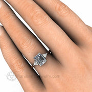 Emerald cut 3 stone gray moissanite engagement ring hand photo