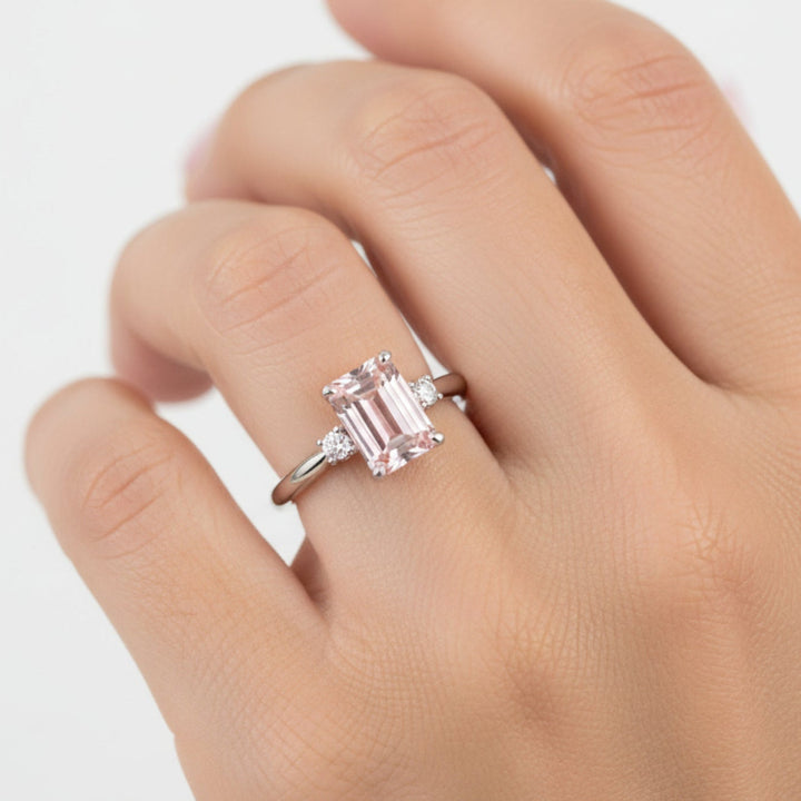 Emerald Cut Pink Morganite Engagement Ring in a 3 Stone Design with Diamond Accents shown on a Hand Model | Rare Earth Jewelry