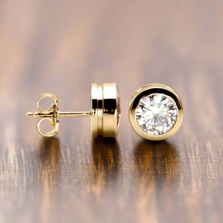 14K Gold Moissanite stud earrings in 1 carat, 1.5 carat and 2 carat sizes.  Modern minimalist bezel set design.