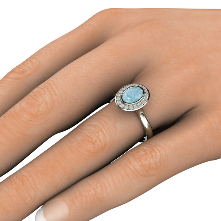 Oval Aquamarine Engagement Ring Bezel Set with Diamond Halo shown on a the Finger.