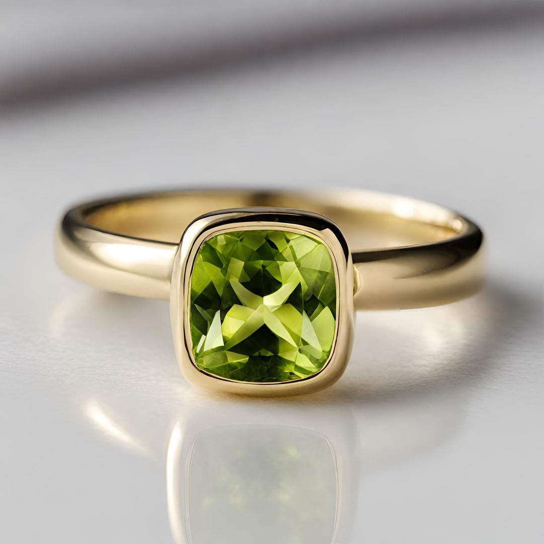 A simple Peridot ring with a cushion cut natural Peridot in a clean, sleek bezel set solitaire design from Rare Earth Jewelry.