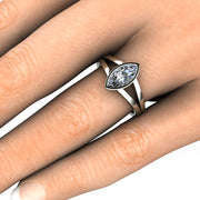 A 1ct marquise cut Moissanite engagement ring with a split shank and bezel setting on the finger hand photo.