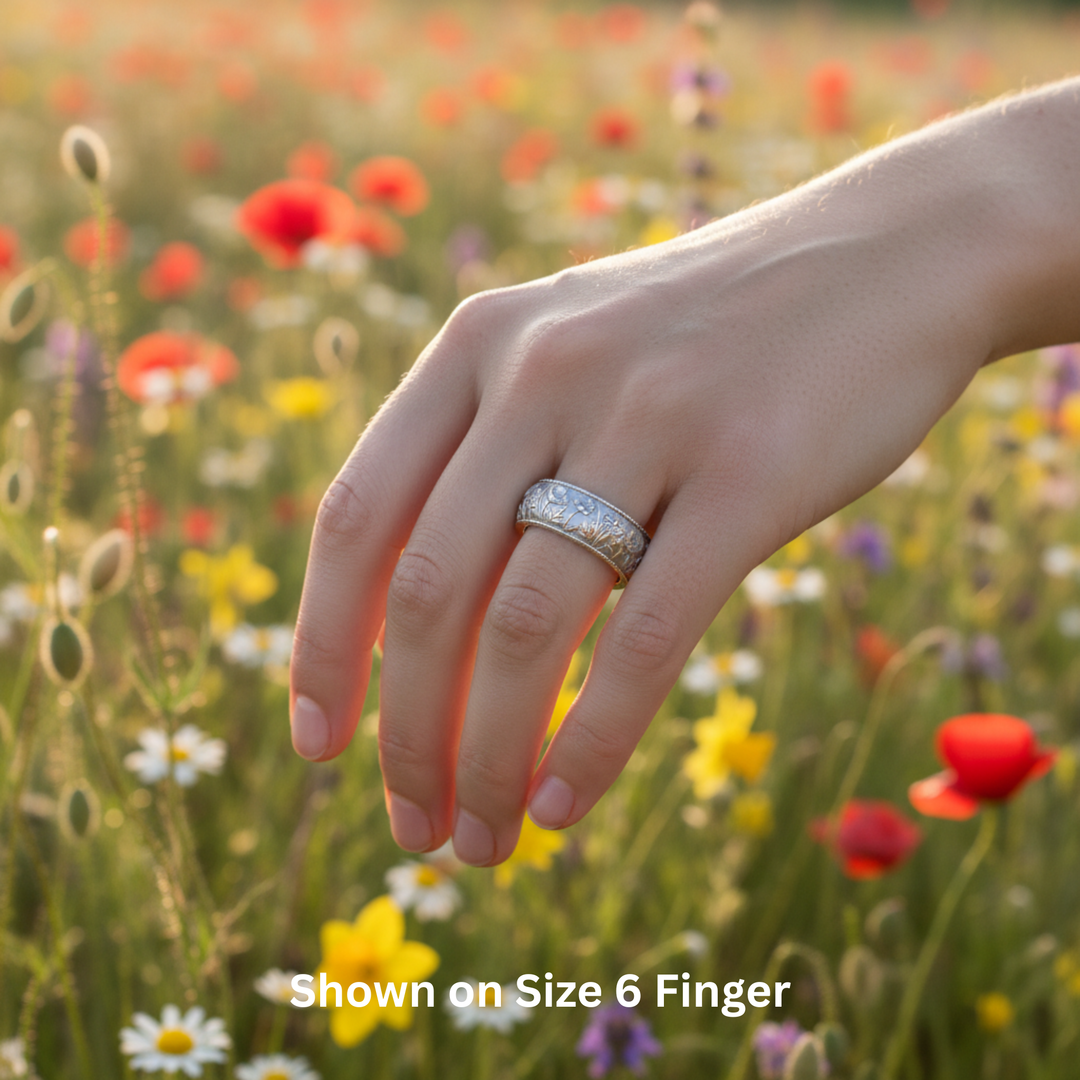 Spring flowers wedding band shown on the hand.  Engraved floral design with poppy, daisy and daffodil, nature inspired botanical ring, 8mm wide band on size 6 finger | Rare Earth Jewelry