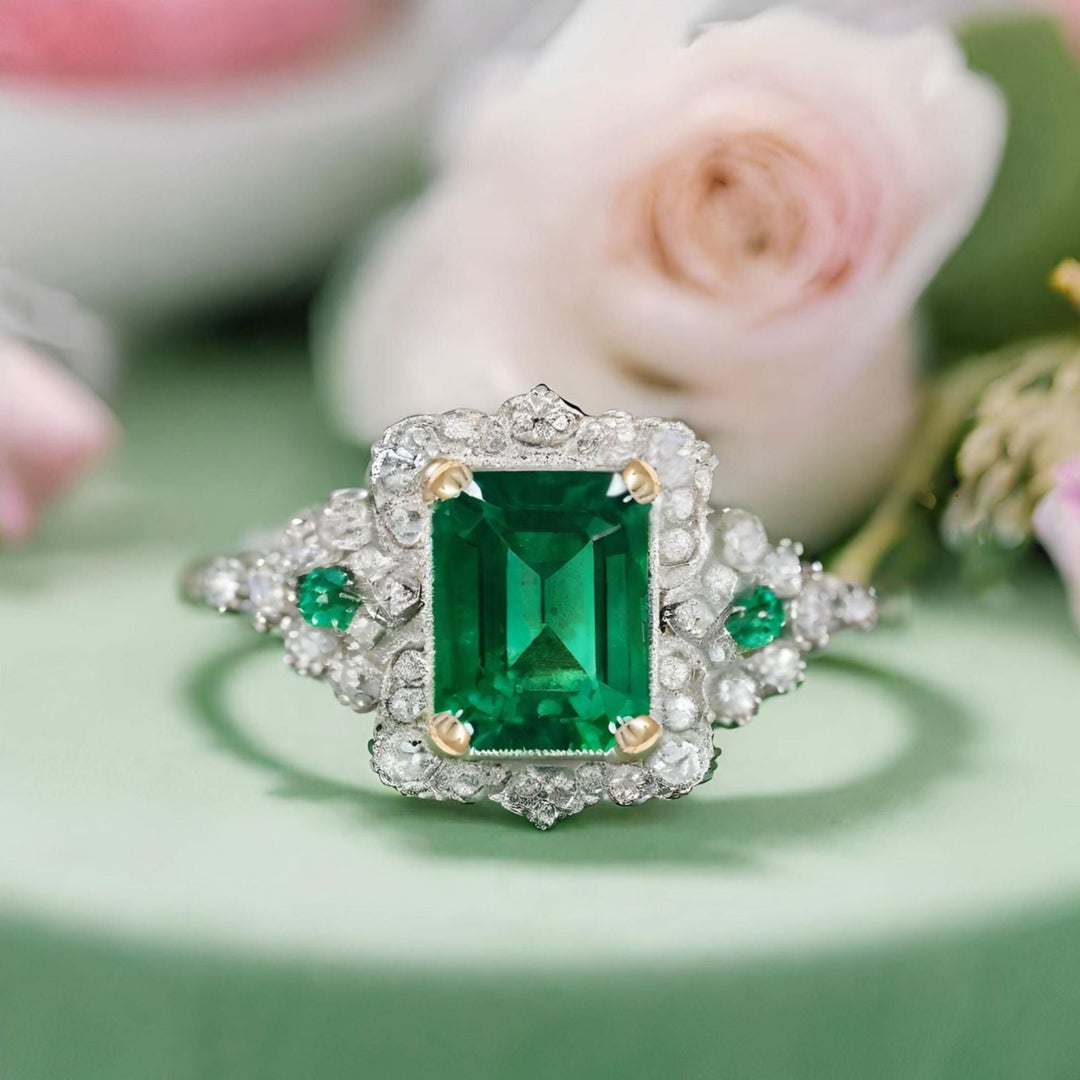 A handmade antique style emerald ring with an emerald cut emerald and an ornate pave diamond design from Rare Earth Jewelry.