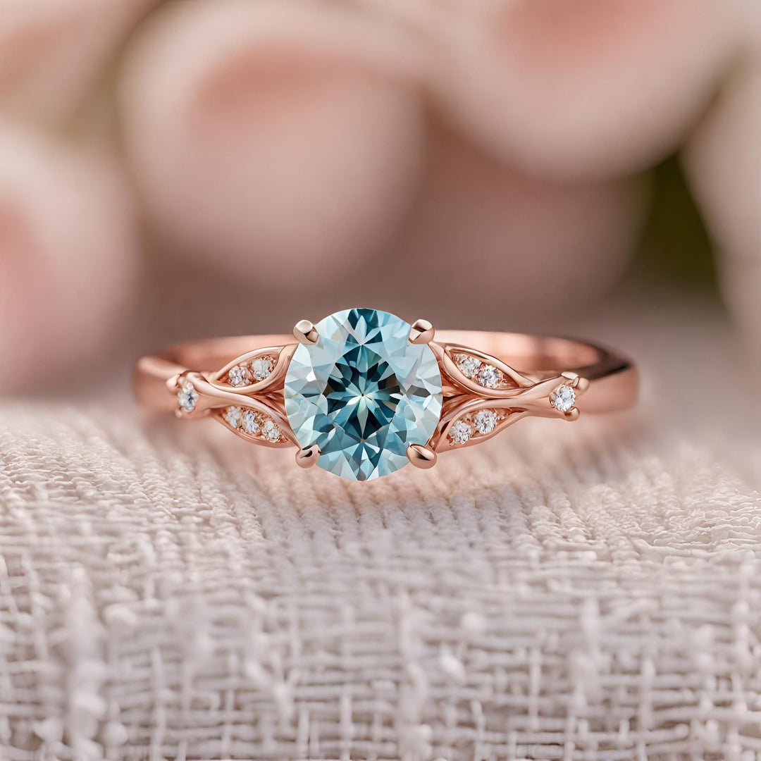 An aqua blue round diamond engagement ring in rose gold with diamond accents from Rare Earth Jewelry.