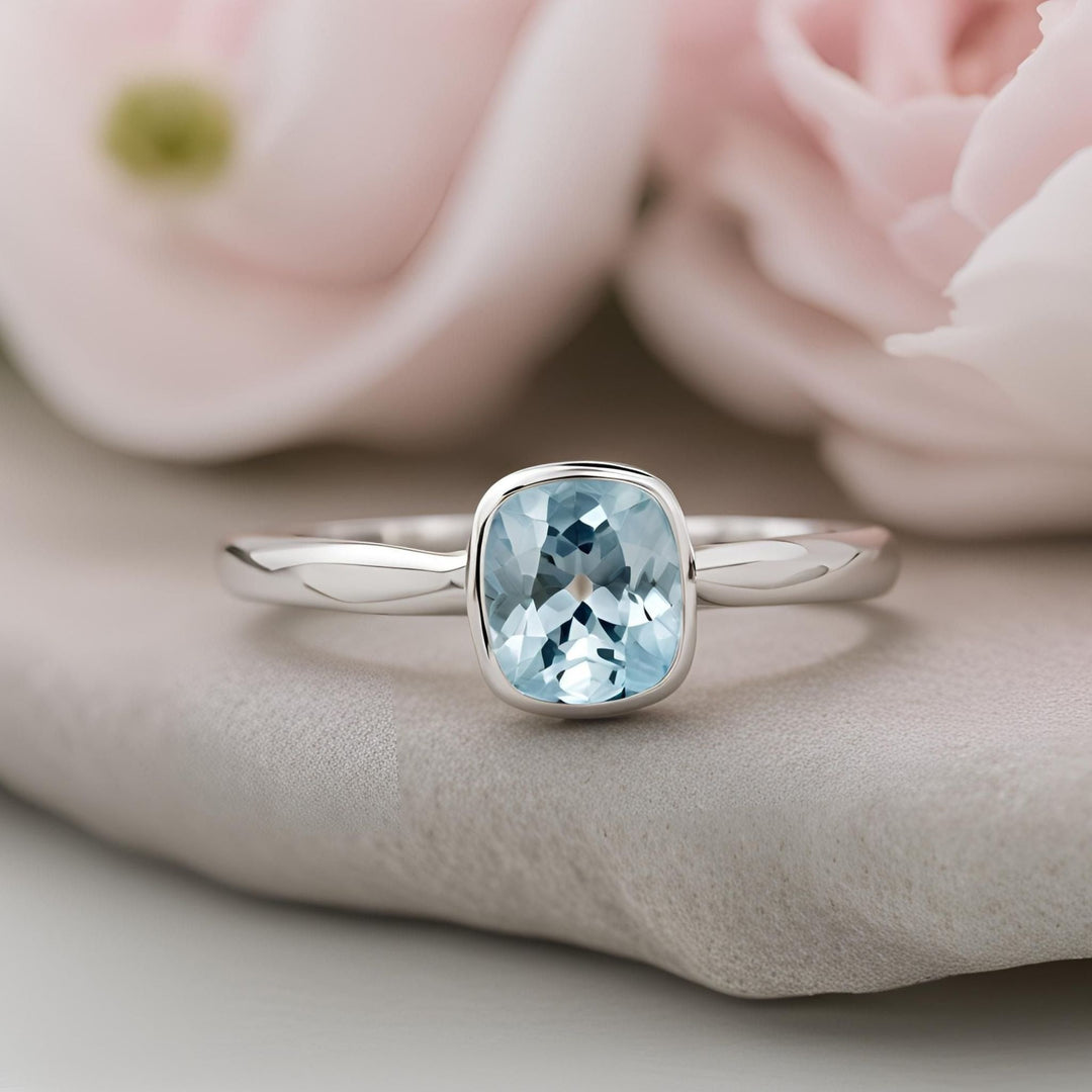 A cushion cut natural aquamarine ring in a simple bezel set solitaire engagement ring setting minimalist style from Rare Earth Jewelry.