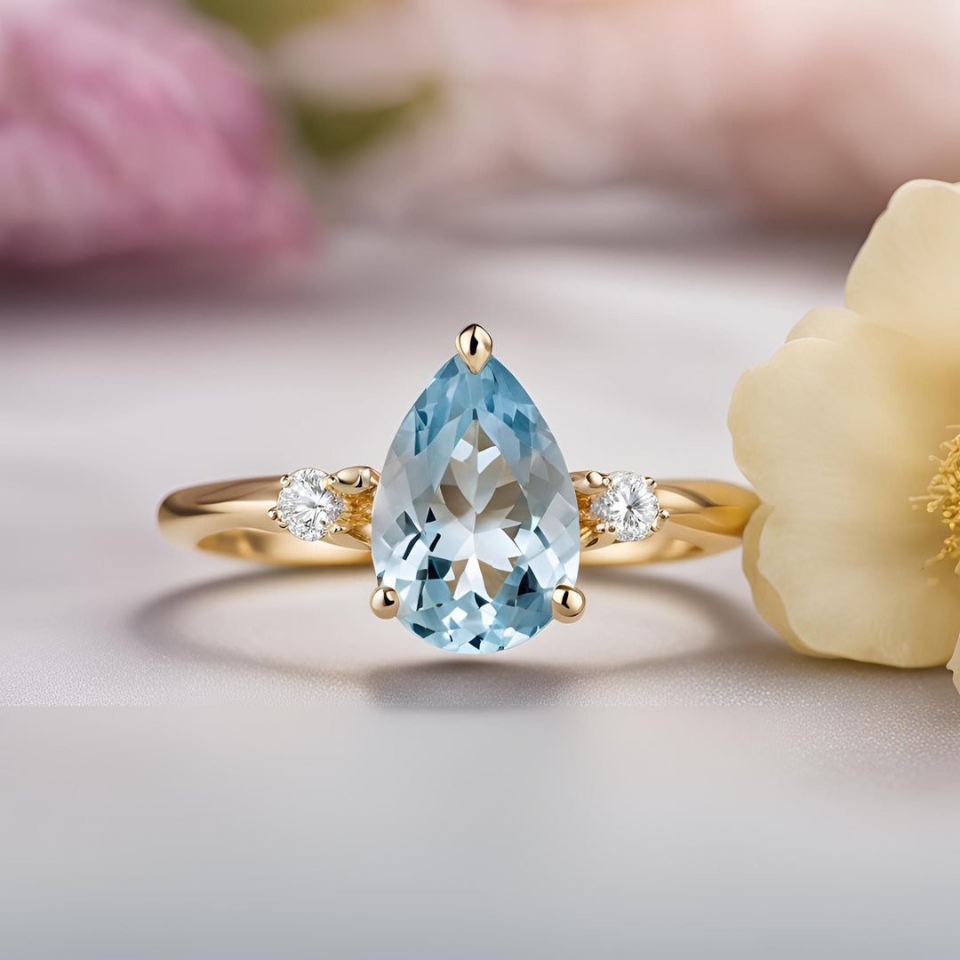 An Aquamarine pear engagement ring in a classic 3 stone design with diamond accents from Rare Earth Jewelry.