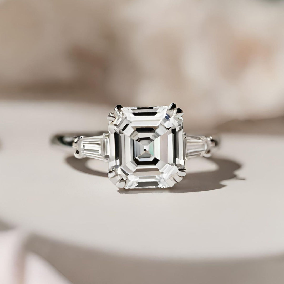 A three-stone engagement ring with a stunning Asscher cut lab-grown diamond and sparkling baguettes from Rare Earth Jewelry.