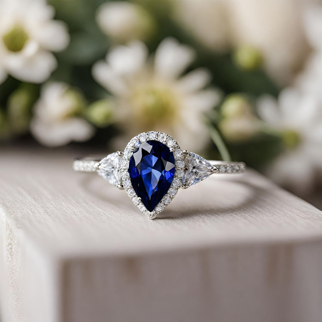 A blue sapphire pear shaped engagement ring with pave set diamonds and diamond trillions in white gold from Rare Earth Jewelry.