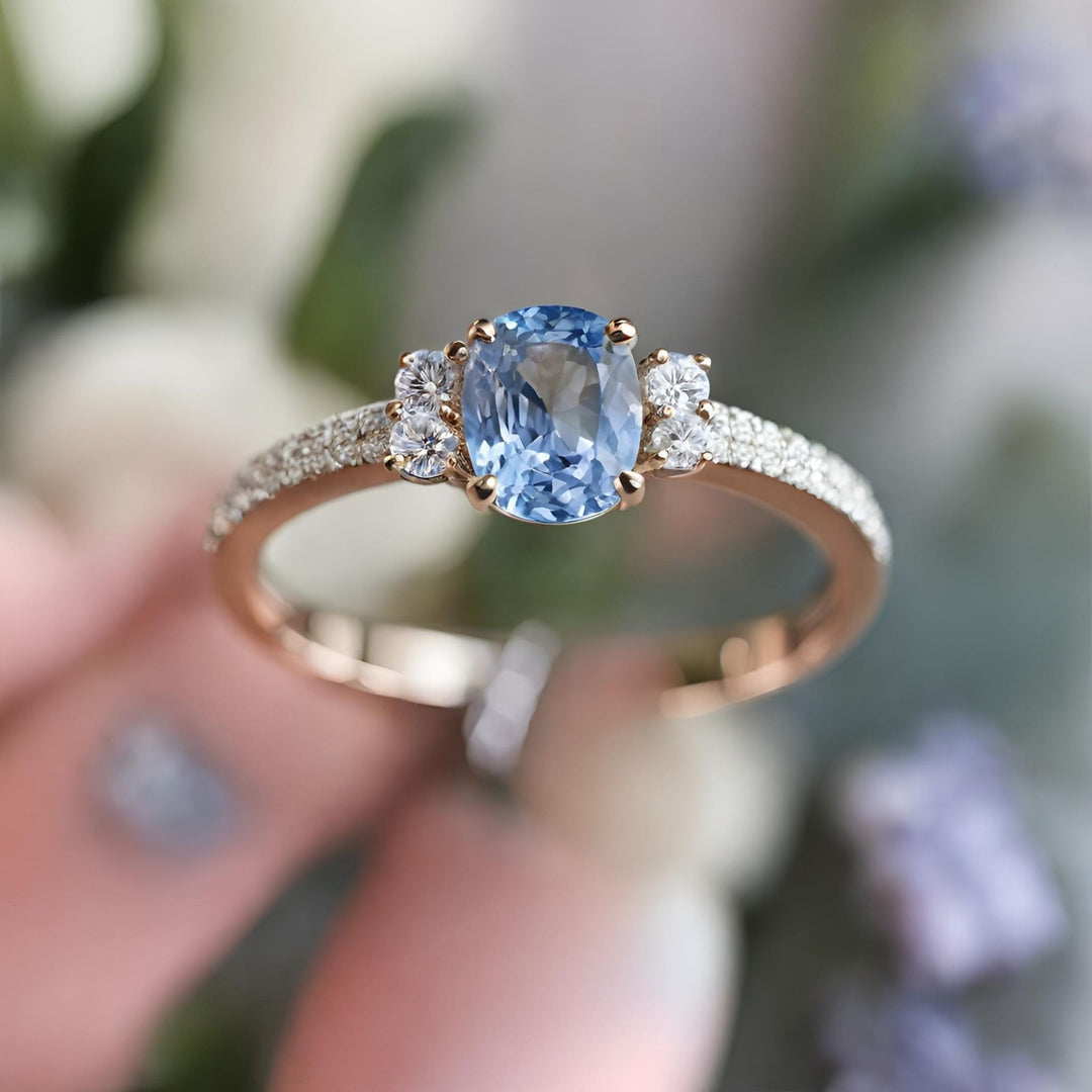 A cushion cut Ceylon light blue sapphire engagement ring with pave diamonds in 18K Gold from Rare Earth Jewelry.