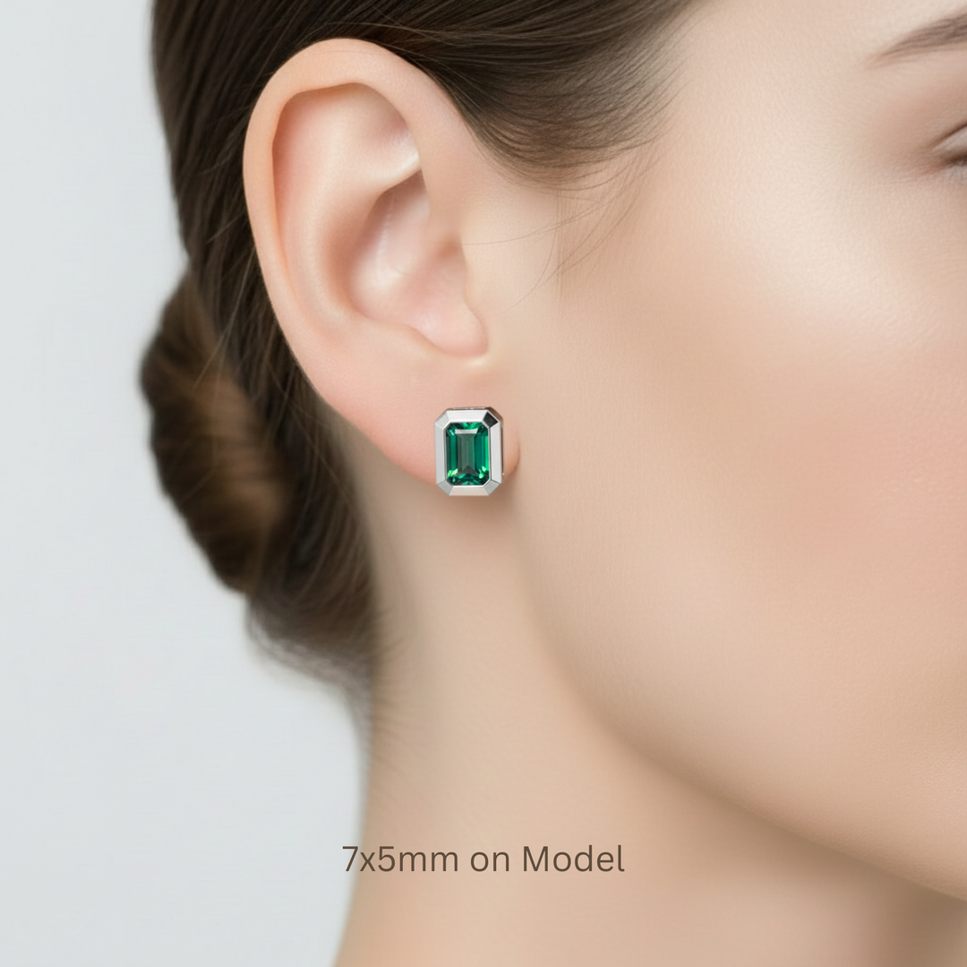 7x5mm classic size lab grown emerald stud earrings, bezel set and shown on ear | Rare Earth Jewelry