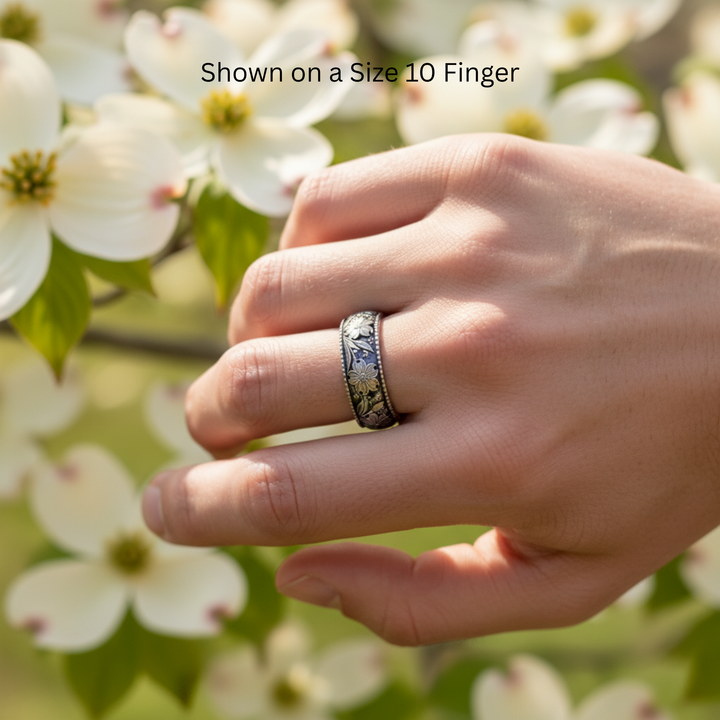 Dogwood blossom engraved wedding band with dark patina shown on size 10 men’s hand, 8mm botanical floral ring, custom wedding ring | Rare Earth Jewelry