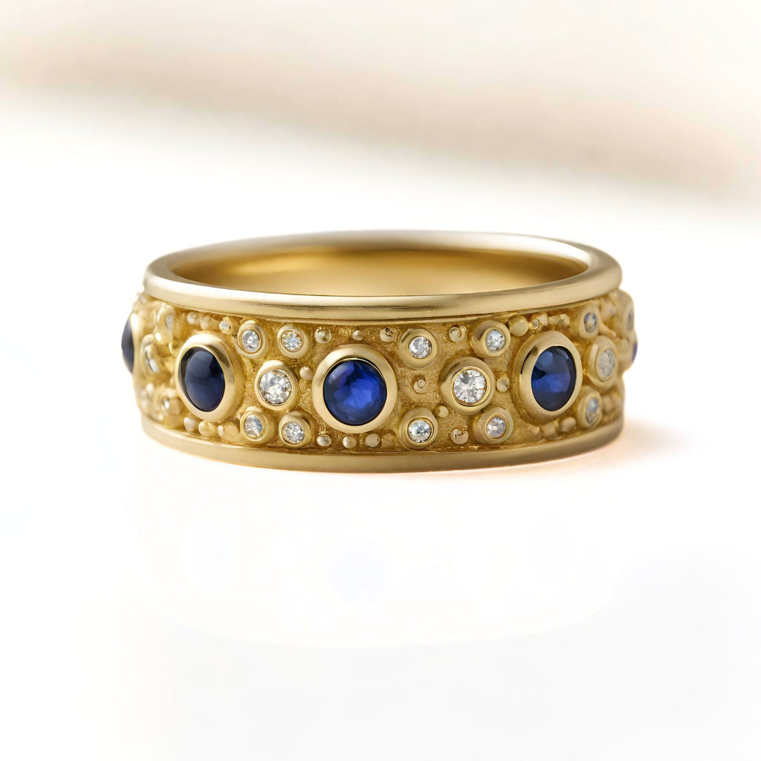 A blue sapphire and diamond band with bezel set stones and an etruscan design in yellow gold from Rare Earth Jewelry.