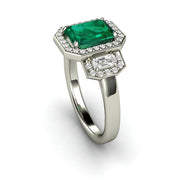 Green lab grown emerald engagement ring with a three stone halo design in white gold.