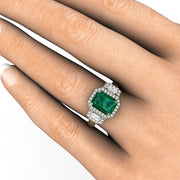 Large Emerald Cut Green Emerald Ring on the hand with a 3 stone style diamond halo.