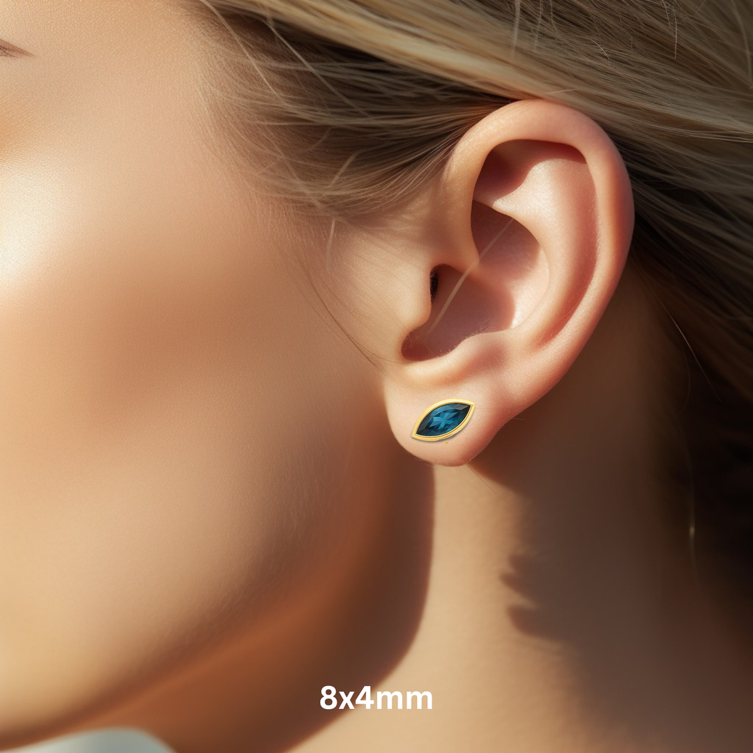 Close Up of London Blue Topaz Stud Earrings in a 8x4mm Marquise Cut on the Ear, 14K Yellow Gold Bezel Set Blue Gemstone Studs for Men or Women.  December birthstone earrings available as single earring or in pairs. | Rare Earth Jewelry