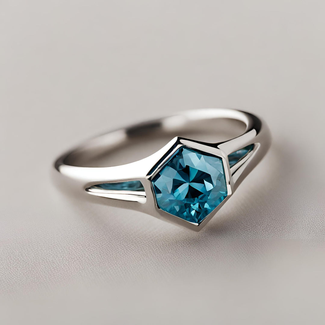 A hexagon cut blue moissanite ring with a modern bezel set design in white gold from Rare Earth Jewelry.