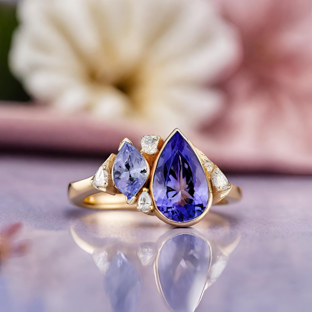 A modern 18K Gold multistone Tanzanite ring with a pear cut natural Tanzanite and diamond accents in a contemporary cluster design from Rare Earth Jewelry.