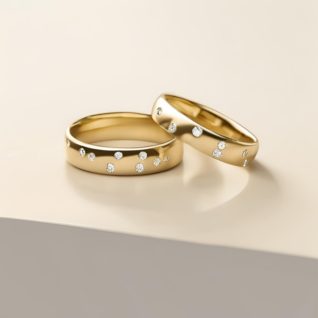 A pair of modern 18K gold wedding bands with gypsy set diamonds in a random design from Rare Earth Jewelry.