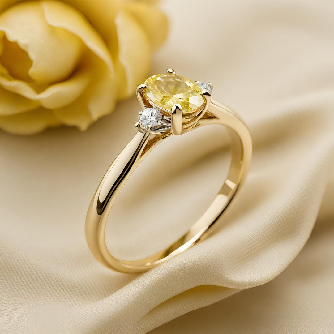 An oval natural yellow sapphire engagement ring in a solitaire design with two diamond accents in yellow gold from Rare Earth Jewelry.