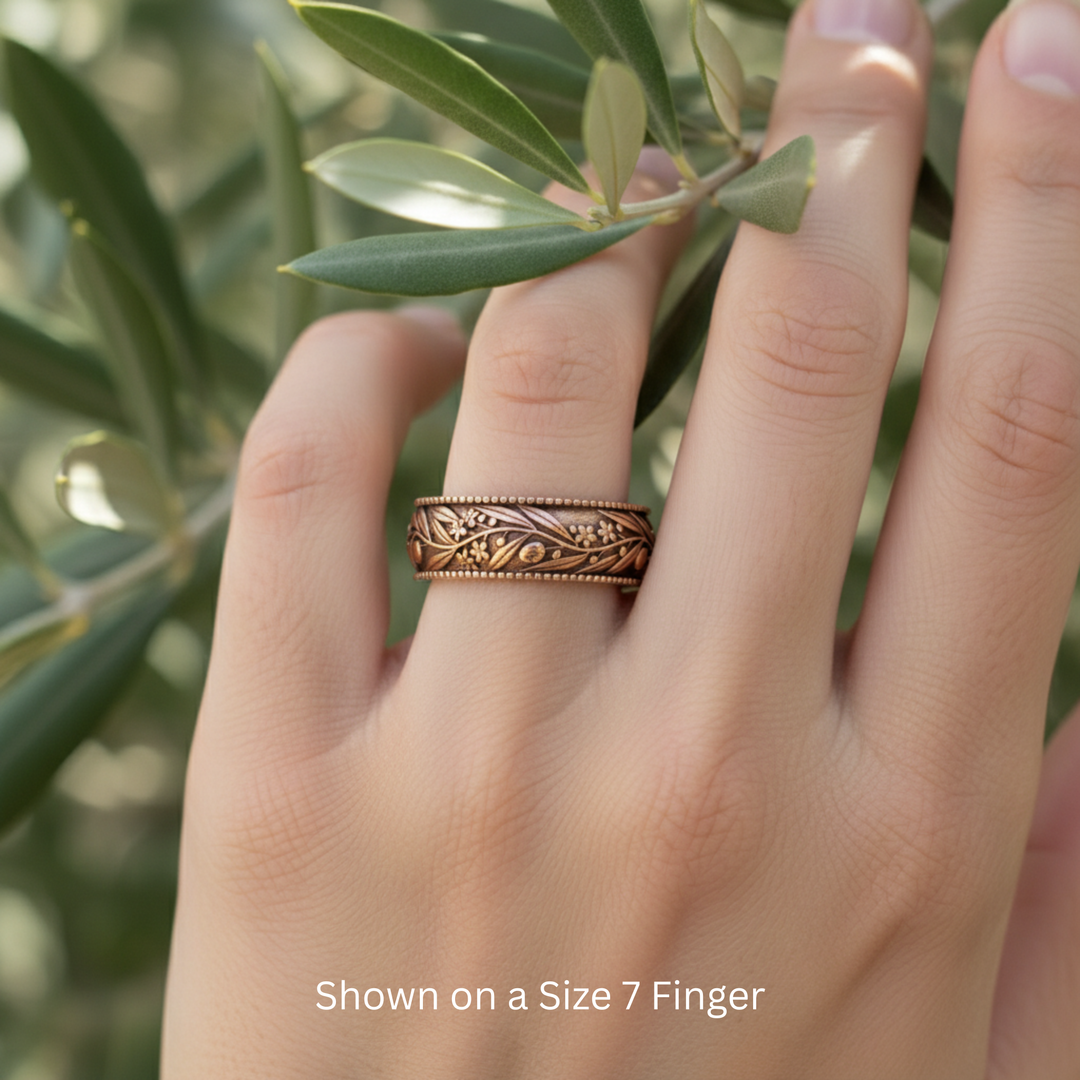 Olive branch wedding band shown in 14K Rose Gold with antique patina on the hand.  Engraved botanical ring with olive branch, leaf, flower and fruit design, unique nature inspired wedding rings | Rare Earth Jewelry 