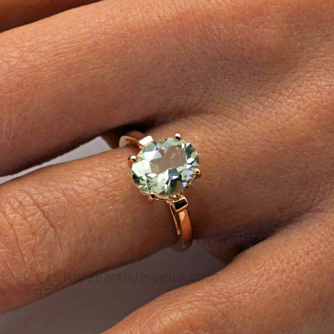 Close up of Oval Cut Green Amethyst Ring Shown on the Hand | Light Green Gemstone in Fleur de Lis Solitaire Design in 14K or 18K Gold