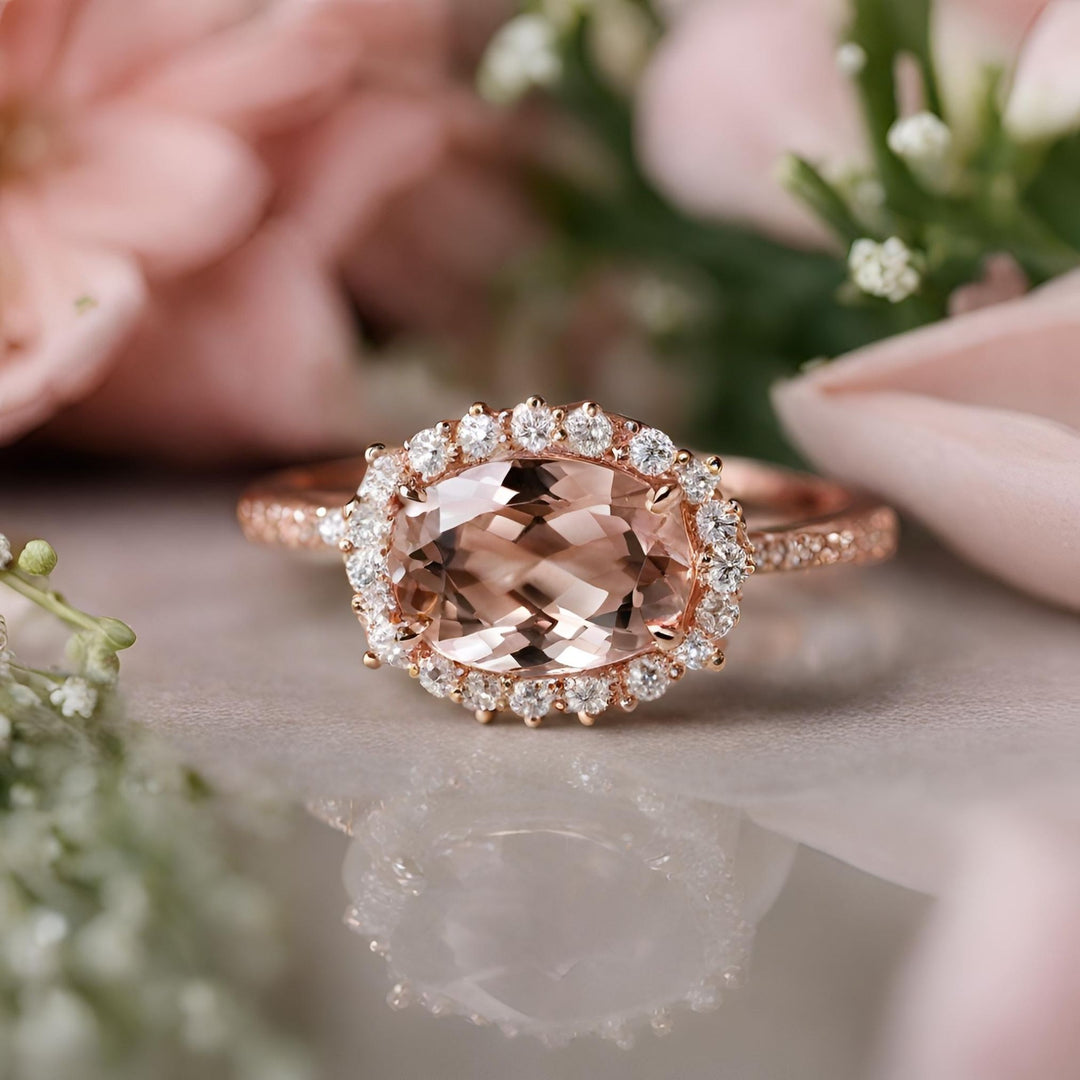 An oval Morganite engagement ring with a unique east to west design with diamonds surrounding the center stone from Rare Earth Jewelry.