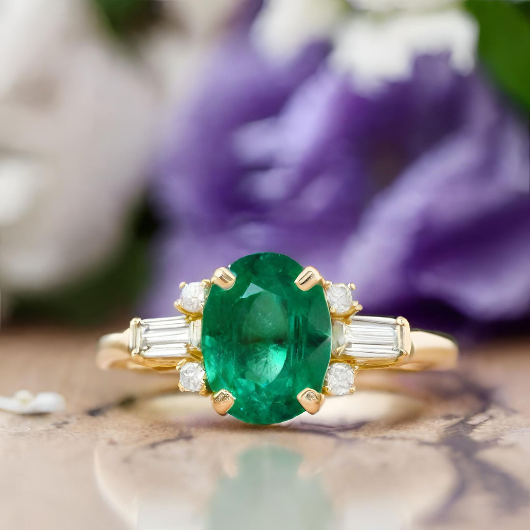 An oval natural emerald ring with diamond baguettes in an updated three-stone style design in 18K Gold from Rare Earth Jewelry.