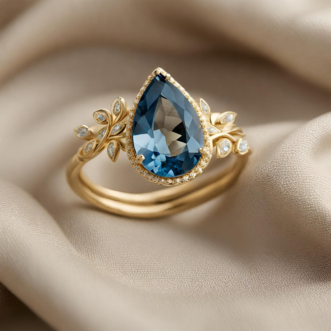 A pear cut London Blue Topaz ring in 18K Gold with a nature inspired leaf and branch design with a diamond accents from Rare Earth Jewelry