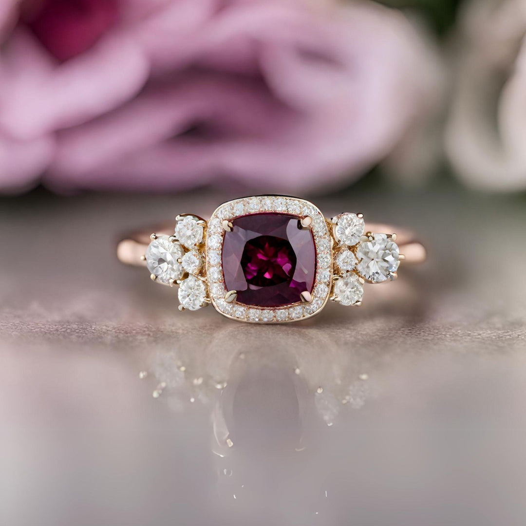 A cushion cut red Garnet engagement ring with diamond halo and accents in rose gold from Rare Earth Jewelry.